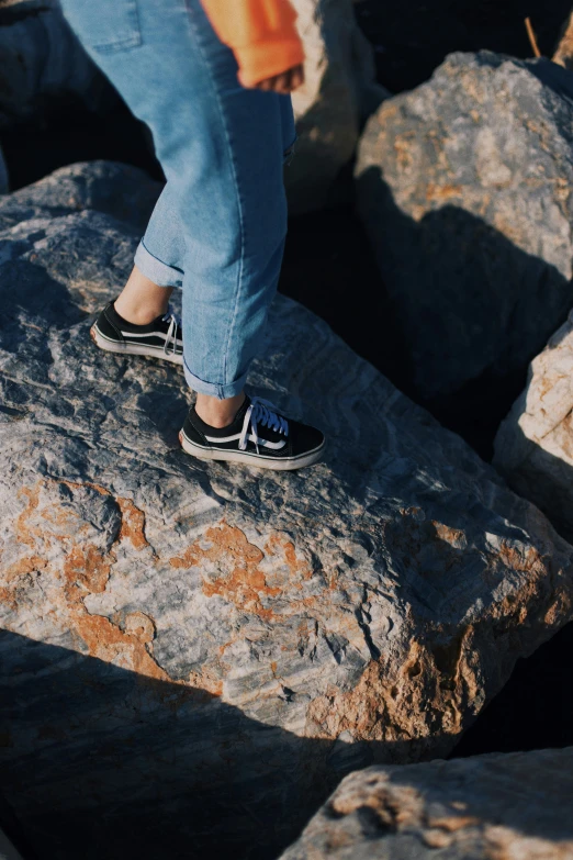 person standing on rocks in daytime sun wearing slippers