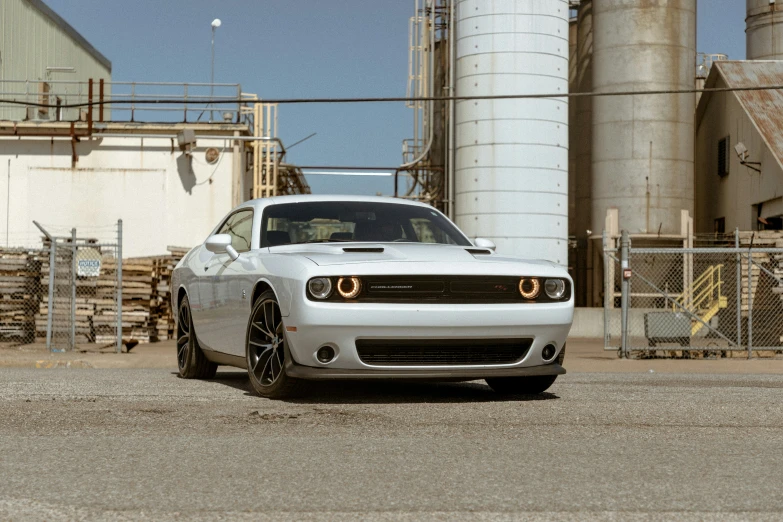 a white sports car parked in front of a grain silo