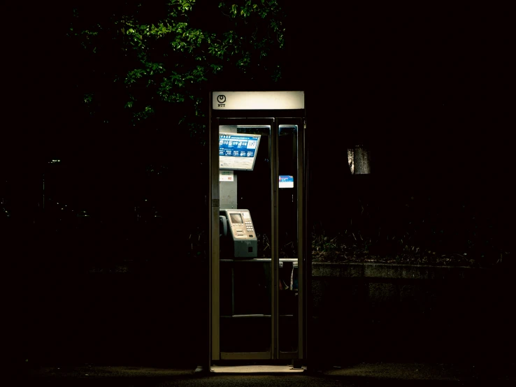 an old telephone box sitting in a dark park