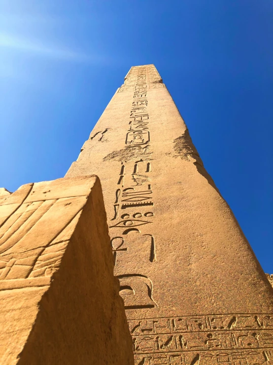 an egyptian pyramid with writing on the side and a bright blue sky behind