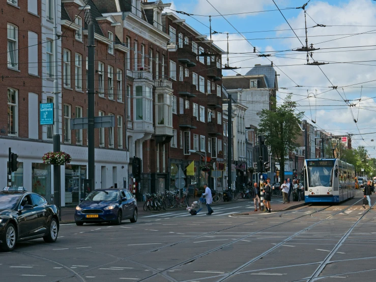 a blue and white train on the tracks next to parked cars