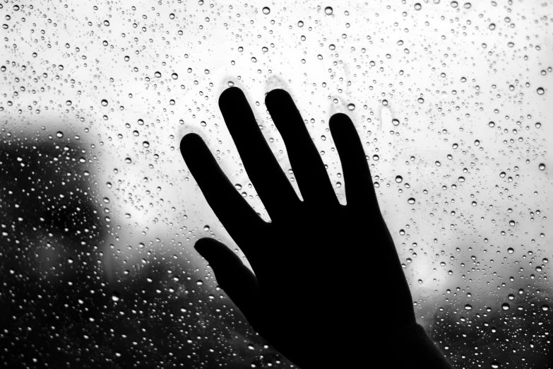 someone's hand is shown through a rain soaked window