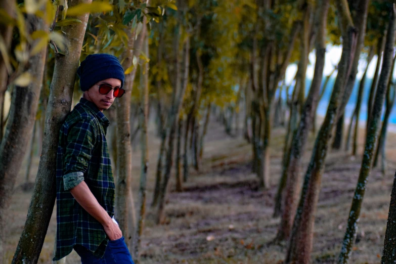 a man with sunglasses on standing under trees