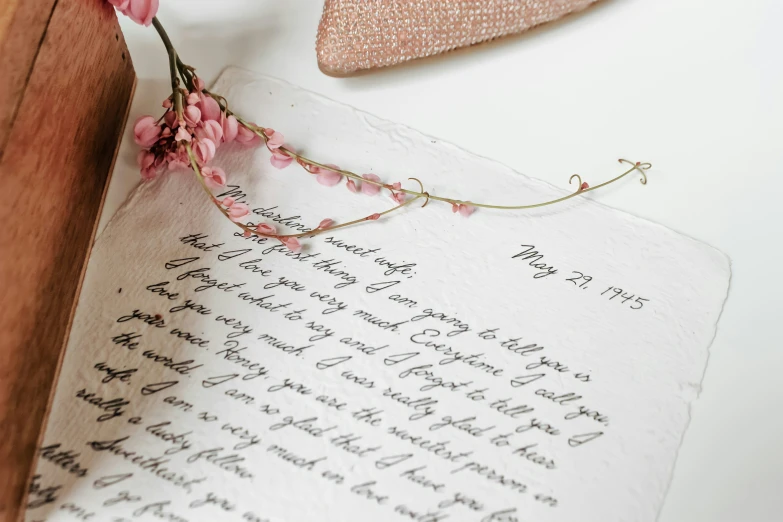 the flowers on the wooden stand are next to a paper and a piece of writing