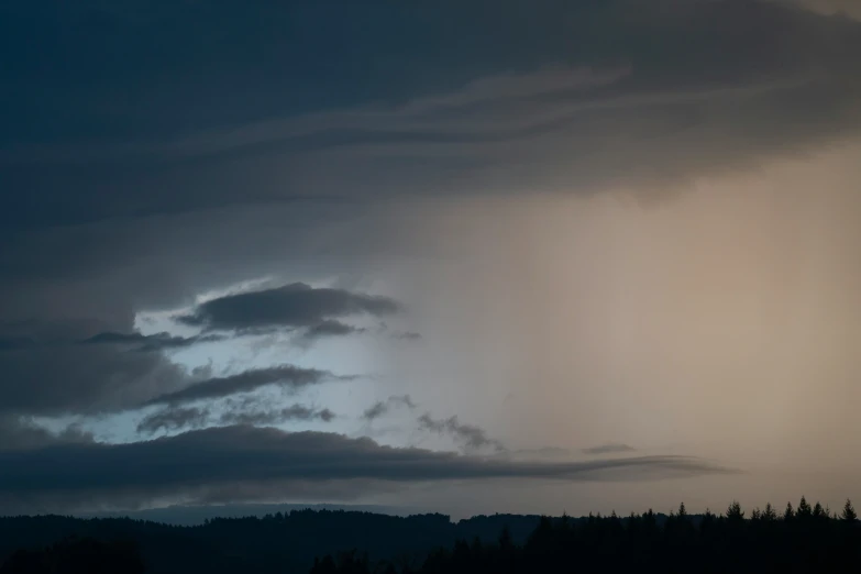 a group of trees and dark clouds are shown