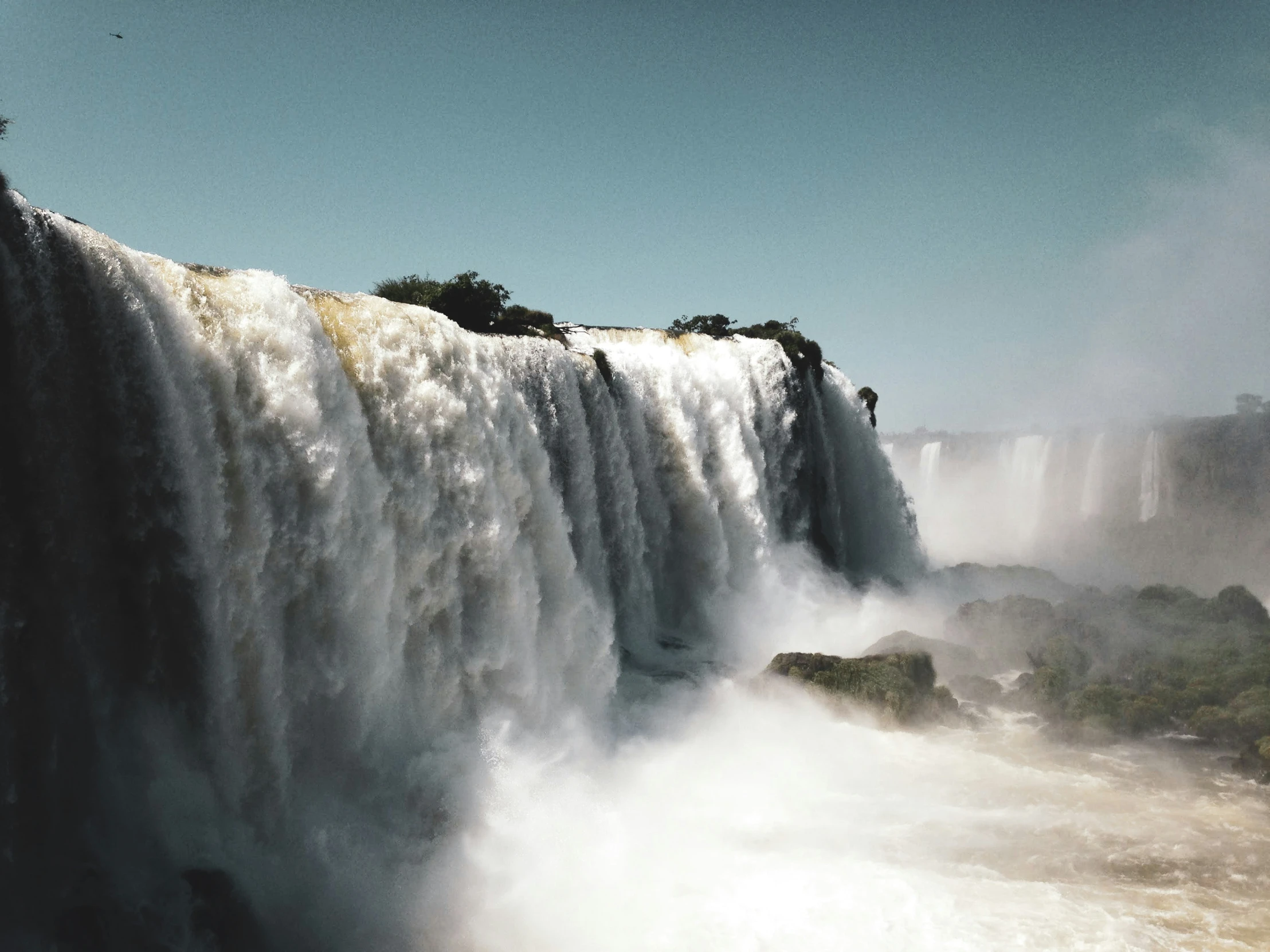 large waterfall with trees and people at the top