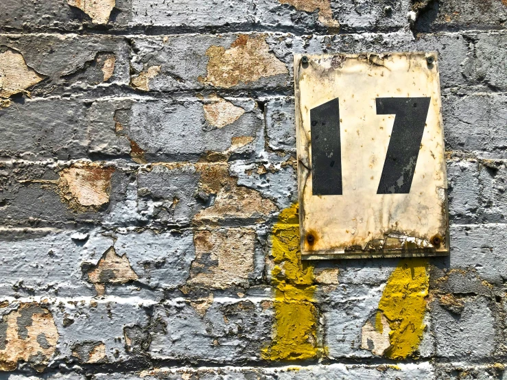 a sign is on a brick wall with yellow painted stripes