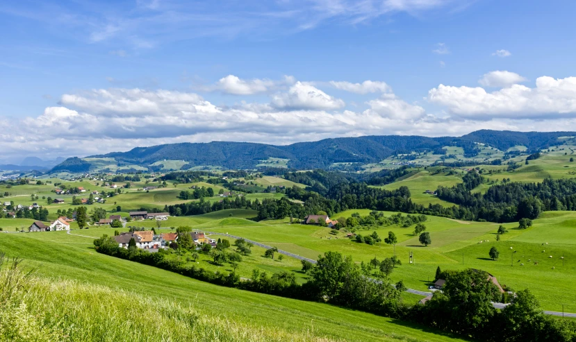green rolling hills and trees are located in the foreground