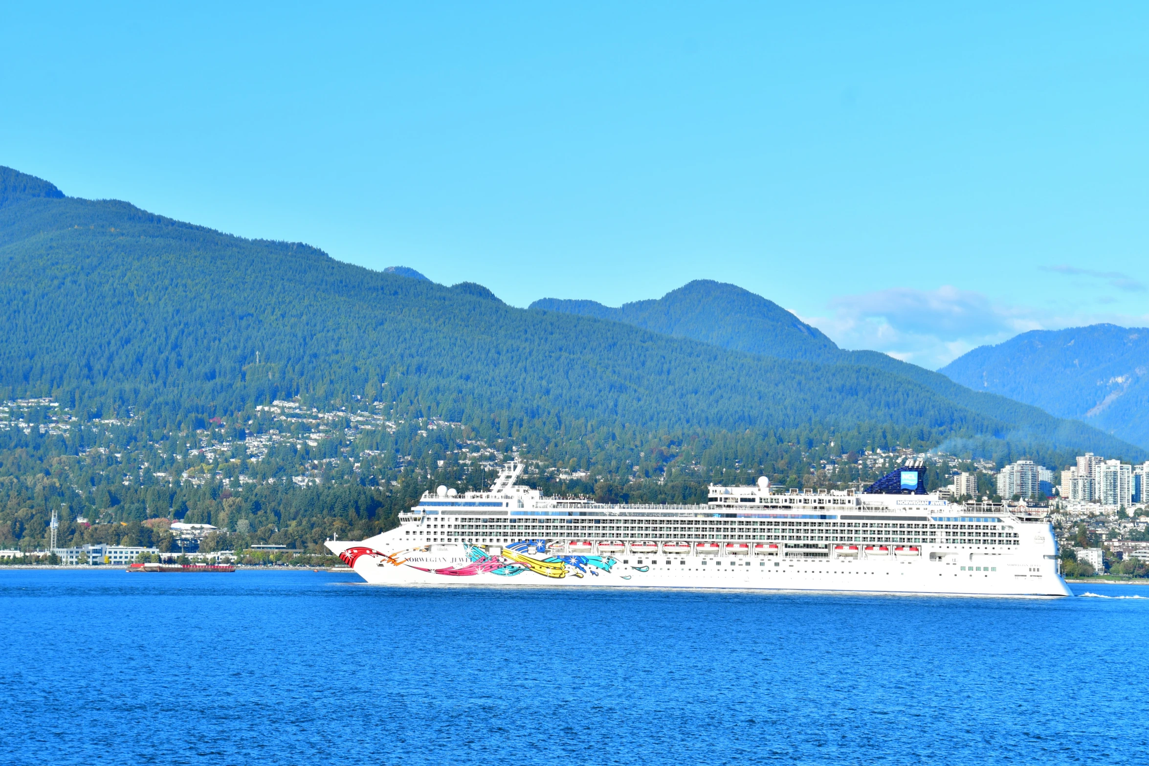 a large boat sailing in the water near mountains