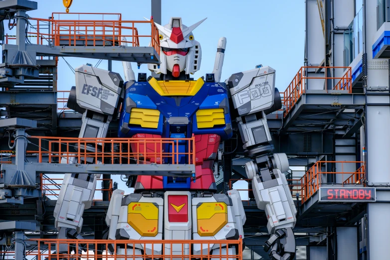 a giant robot with yellow and blue parts is in an open area