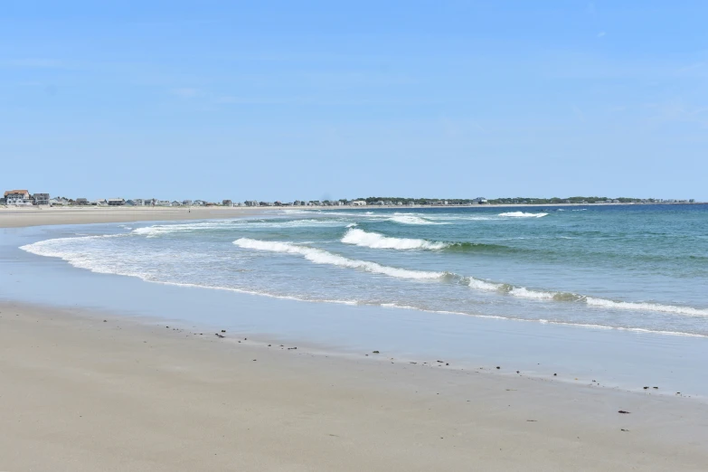 a beach with waves coming in and a kite flying in the sky