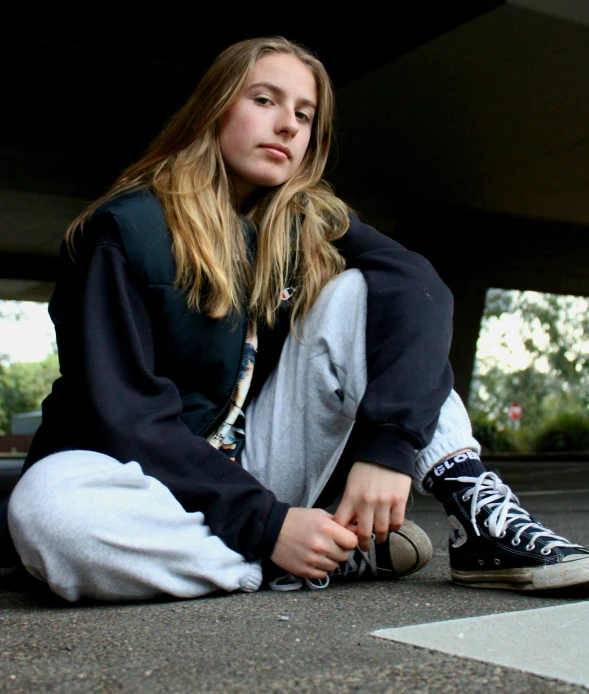 a girl sitting on the ground with a sneaker in her hand