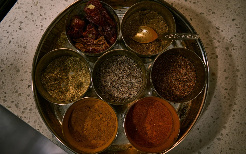 a bowl with seven bowls filled with different spices