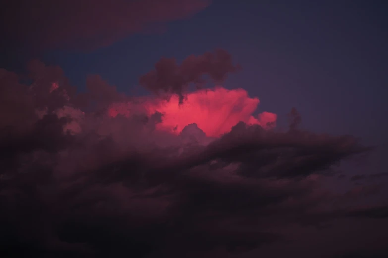 a very dark sky with lots of red clouds