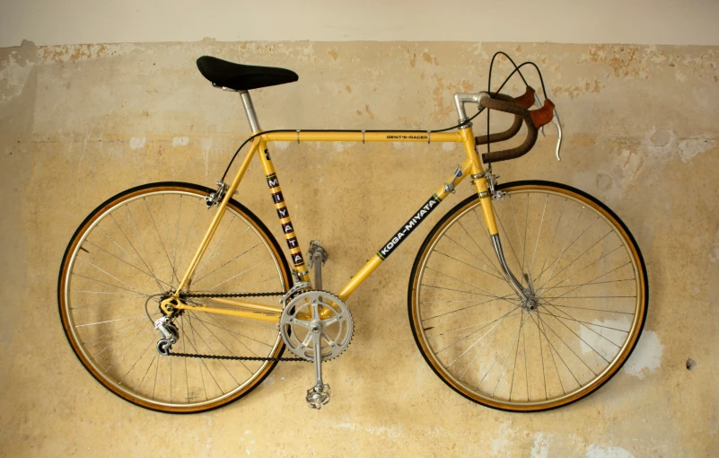 a yellow bike is on a white wall