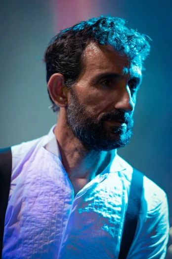 a bearded man is wearing a white shirt and black suspenders