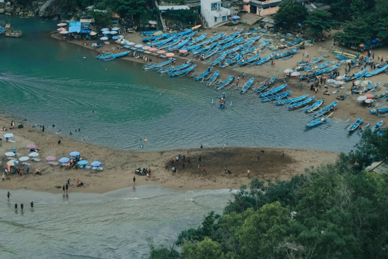 people standing at the beach in front of the boats