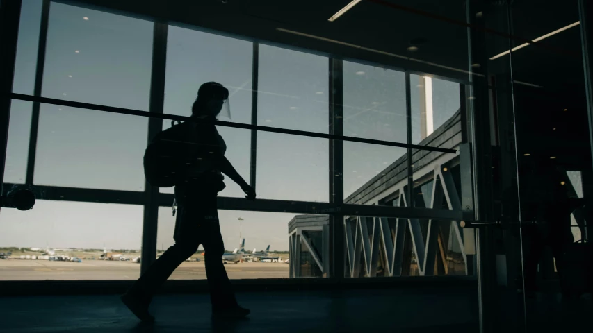 a man walking out an airport terminal with his luggage