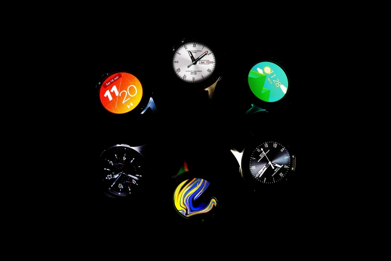 several different colored clocks on a dark night