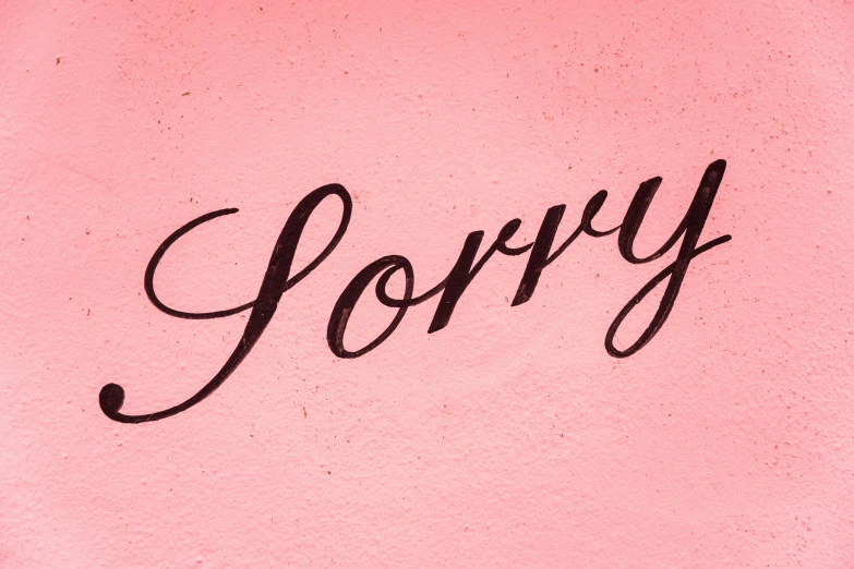 the word sorry written on pink paper with black ink