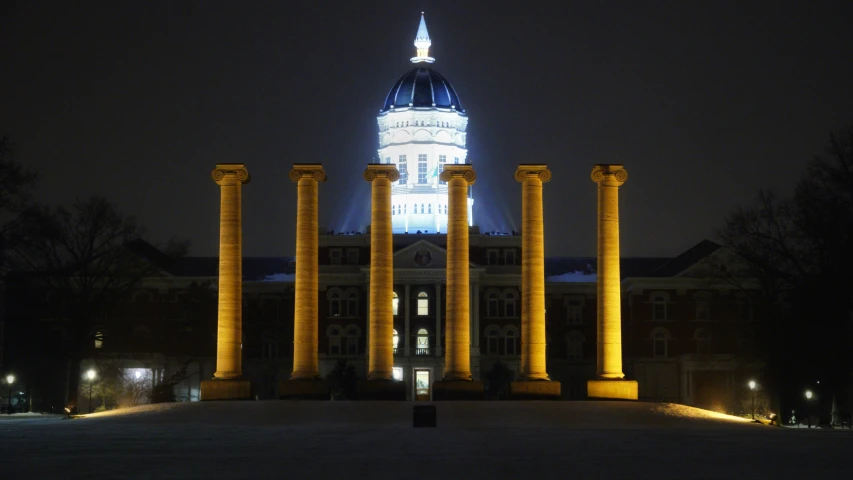 an old building with large columns and a lit up clock tower