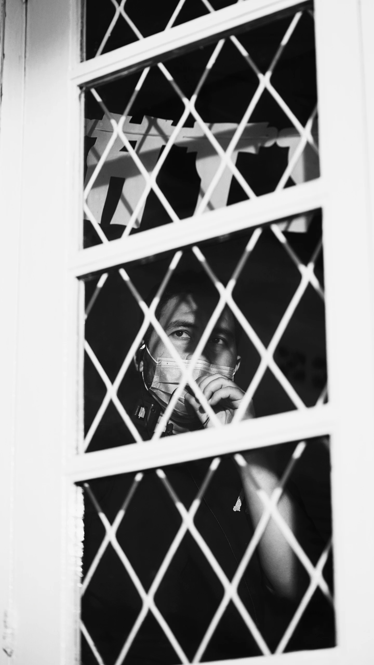 a person is looking through a window with white latticework