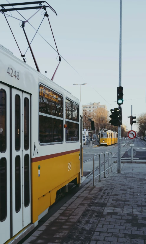 two yellow passenger buses are stopped at an intersection