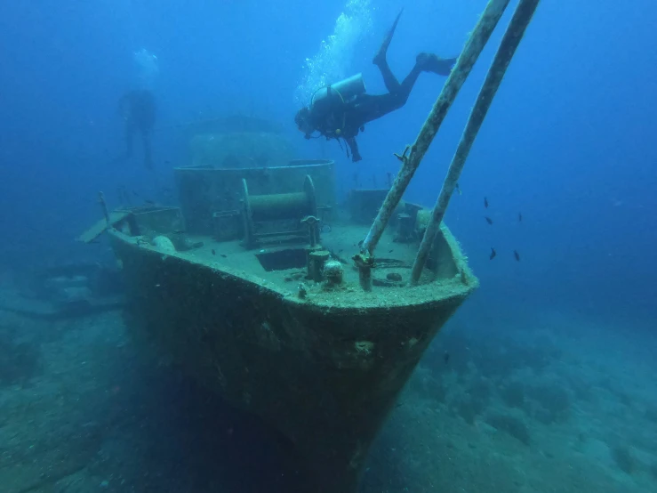 scuba diver swims beside an underwater sunken ship