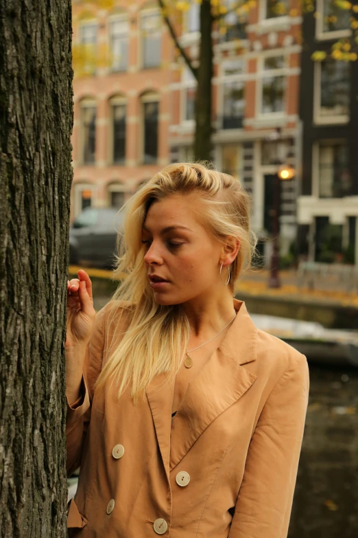 woman leaning against a tree in front of the city