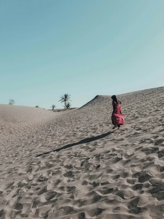 a young person wearing a red jacket is sitting in the sand