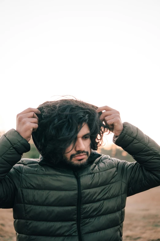 a bearded man holds his hair and stares at the sky