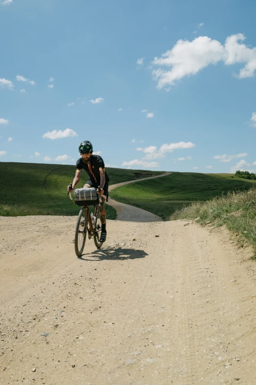 the person is riding their bike on the dirt road