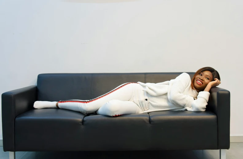a woman wearing white posing for a po with a sofa