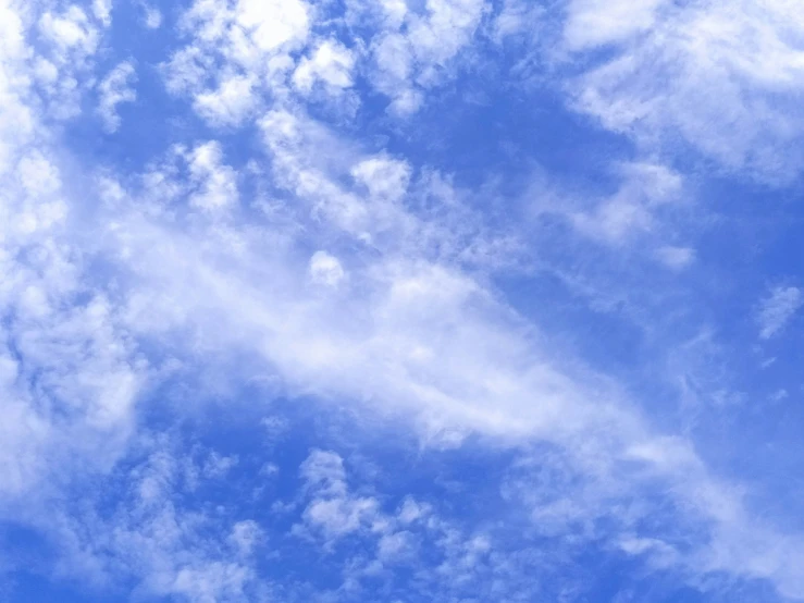 an airplane flying through a blue cloudy sky