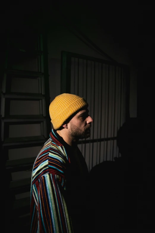 man with yellow hat standing by fence at night