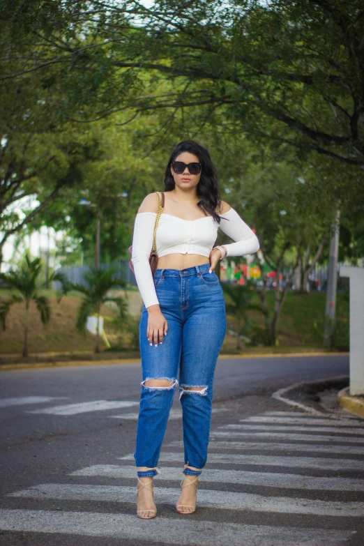 a woman in jeans and white top standing on a road