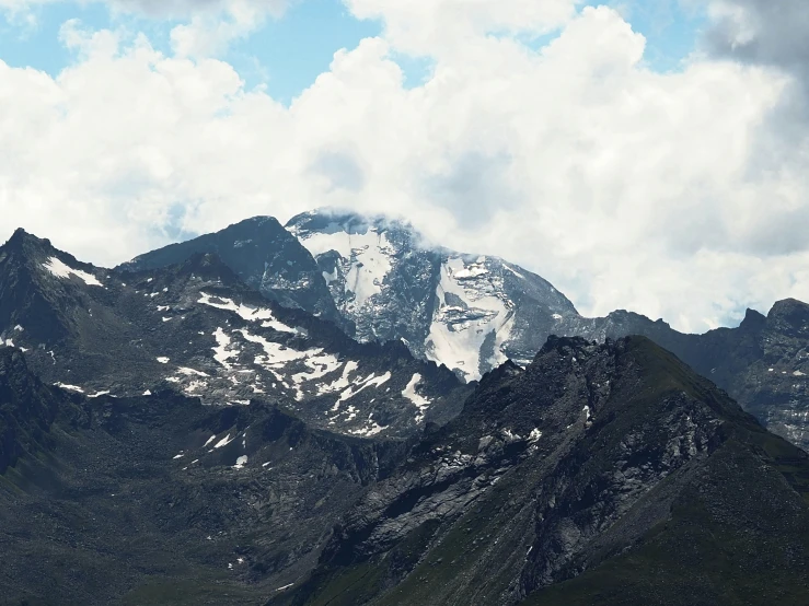 a mountain with a snow covered top under a cloudy sky