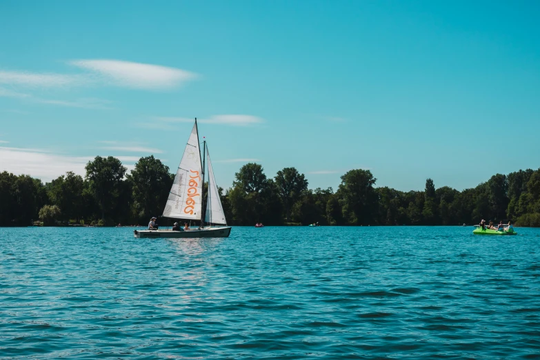 a sailboat sailing on a lake near some trees