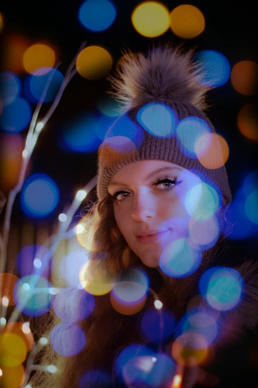 a woman in a winter hat next to a tree