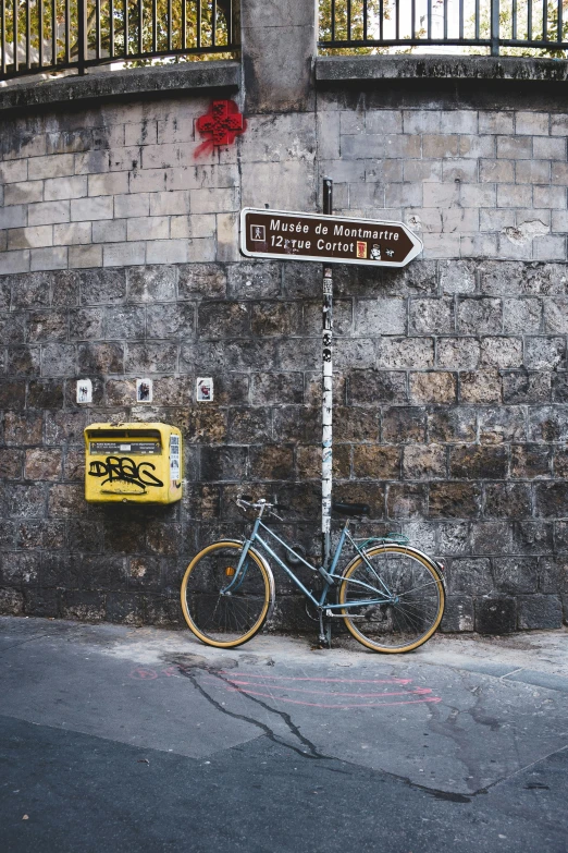 a bicycle is leaned against the wall in front of a street sign