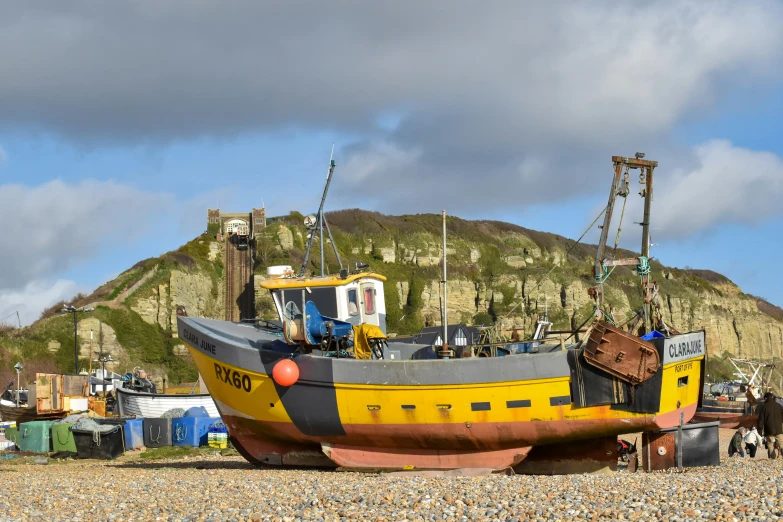 a large boat laying in the sand near a cliff