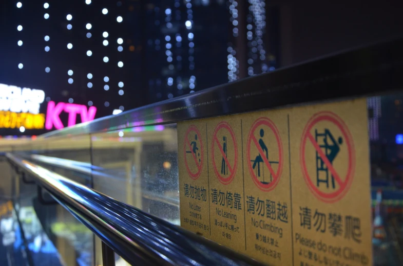 signs posted on railing near subway station at night