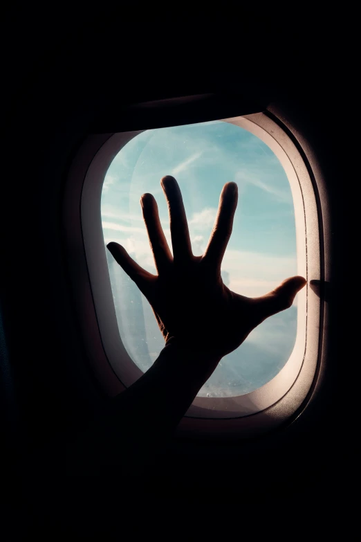 a hand is reaching out the window of an airplane