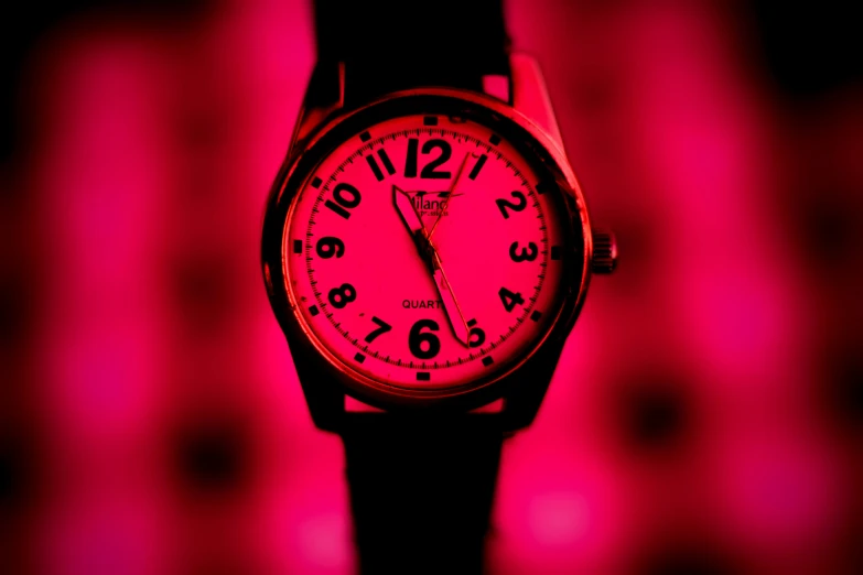 a pink watch lit up on the wrist and behind