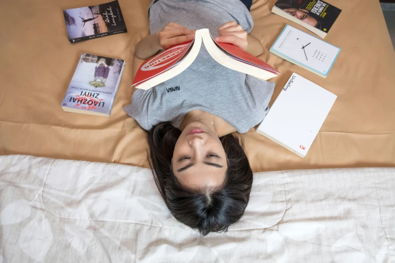 a woman lays on the bed among many books