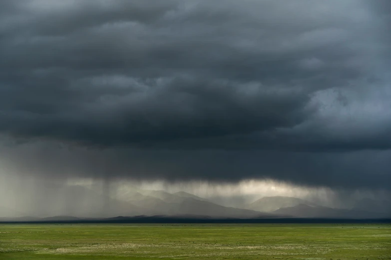 the view from a field in a vast green area with dark clouds overhead