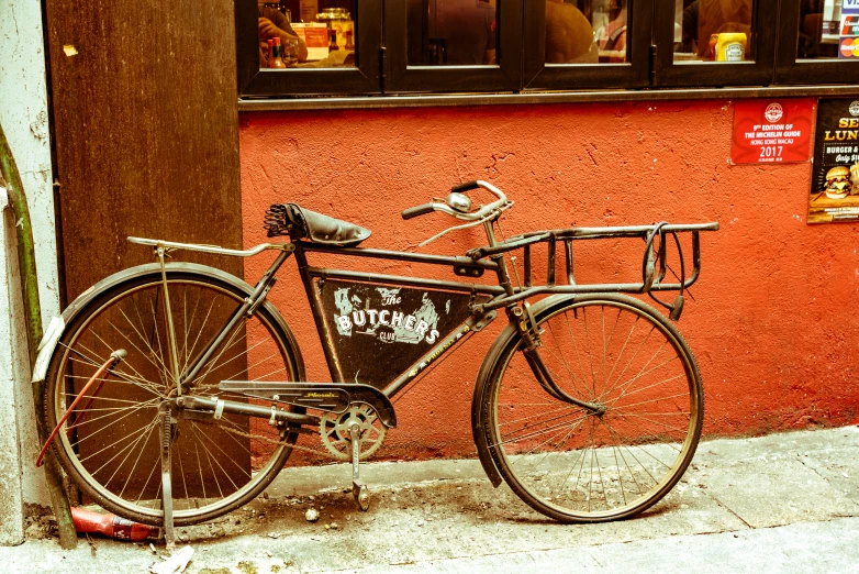 an old bicycle is leaning against a pole on the sidewalk