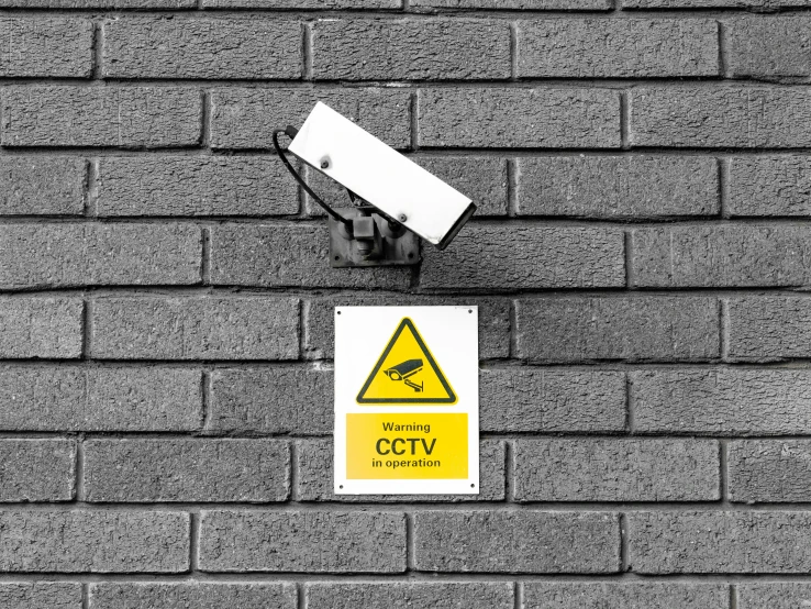 a sign on a brick wall reads caution cctv