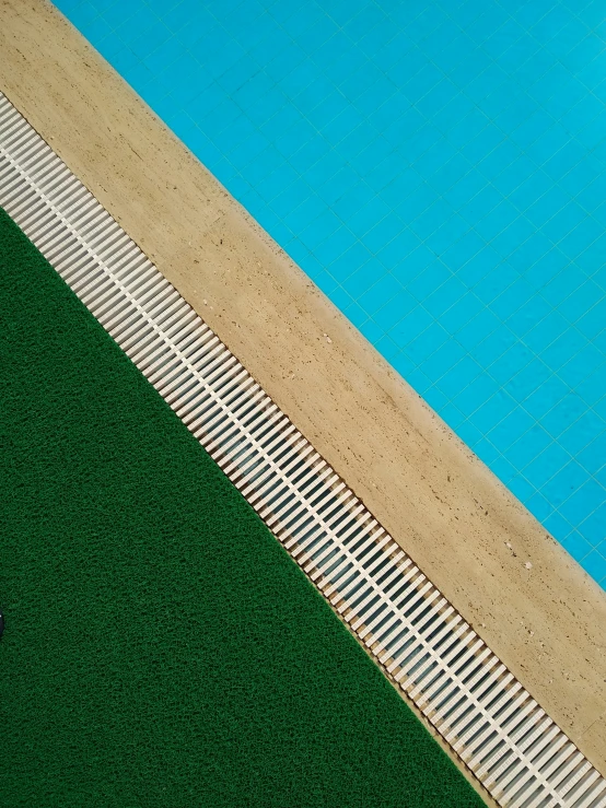 a tiled pool that has green grass and a blue pool