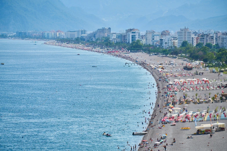 people walking and sitting on beach next to the water